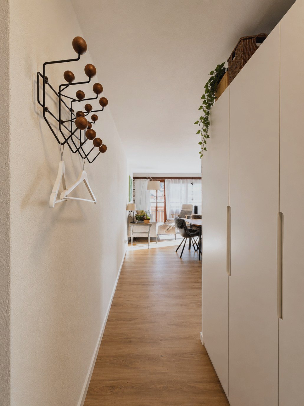 Eingangsbereich in Auri mit Garderobe aus Holz und Metall und Durchblick in den Wohnraum