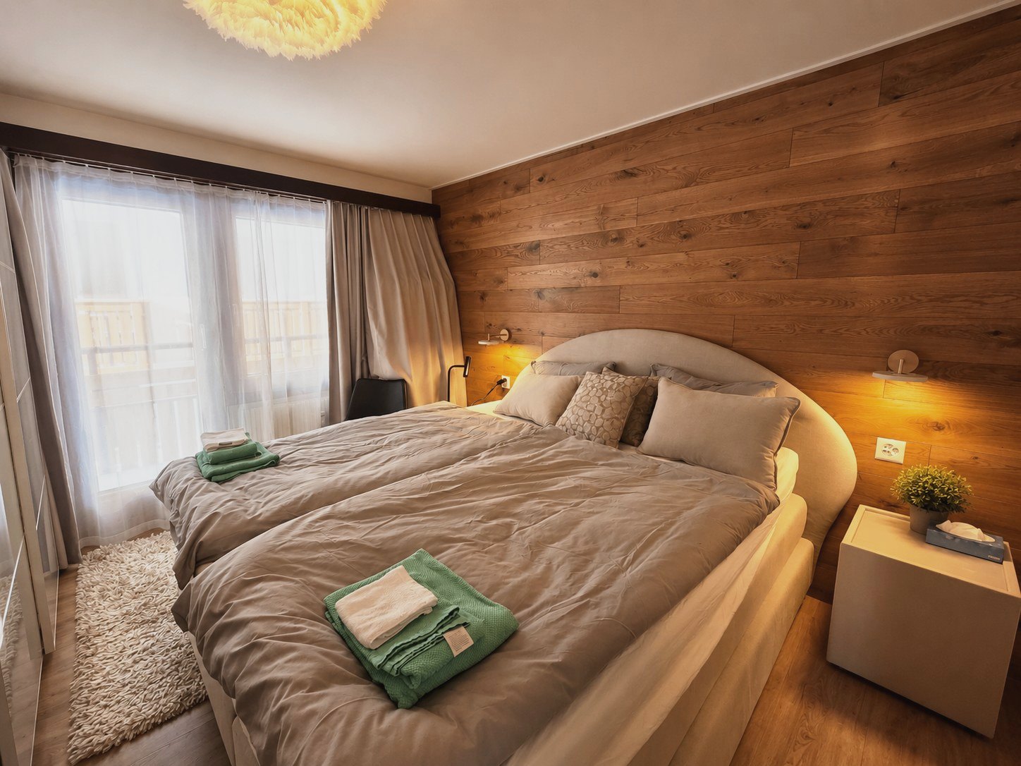 Zweites Schlafzimmer in Auri mit zwei Betten, Holzwand und Blick auf den Balkon