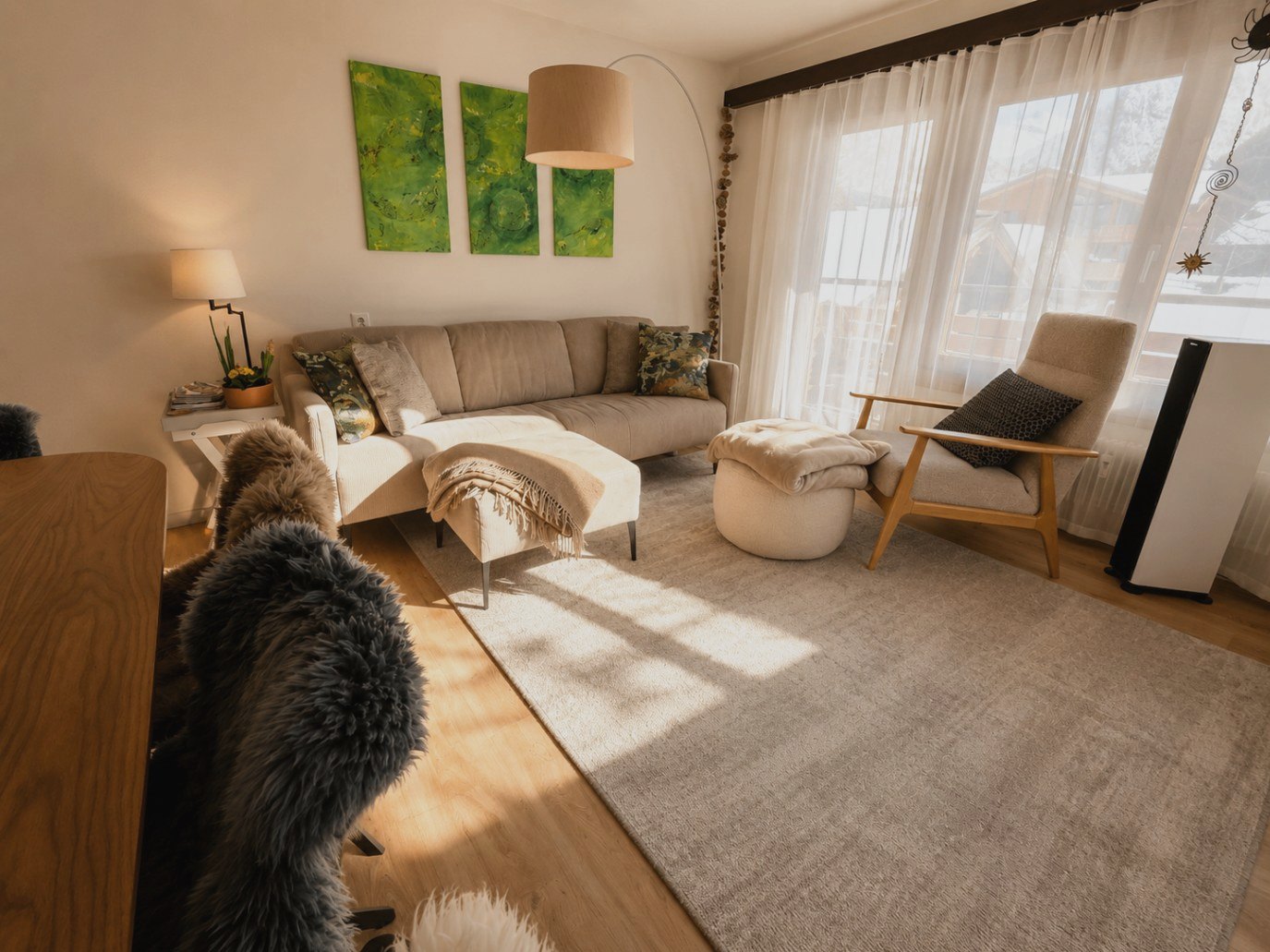 Wohnraum in Auri mit hellem Sofa, Ohrensessel, Bogenlampe und grünen Kunstwerken