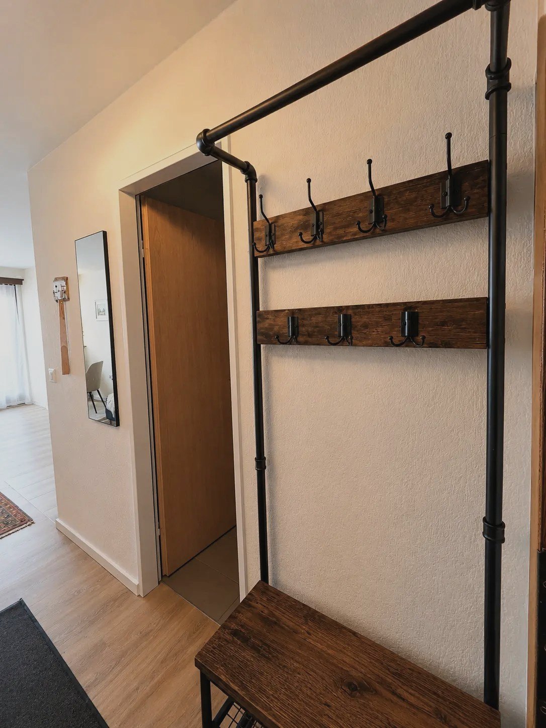 Eingangsbereich des Studios Malo mit Garderobe aus Holz und schwarzem Metall
