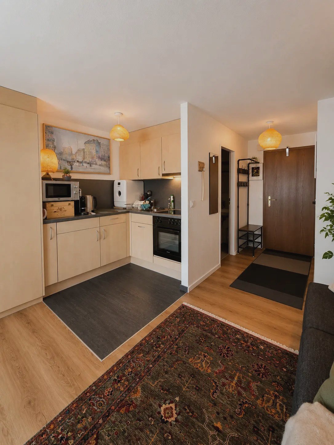 Offene Küche des Studios Malo mit hellen Fronten, Mikrowelle und Blick zum Eingang