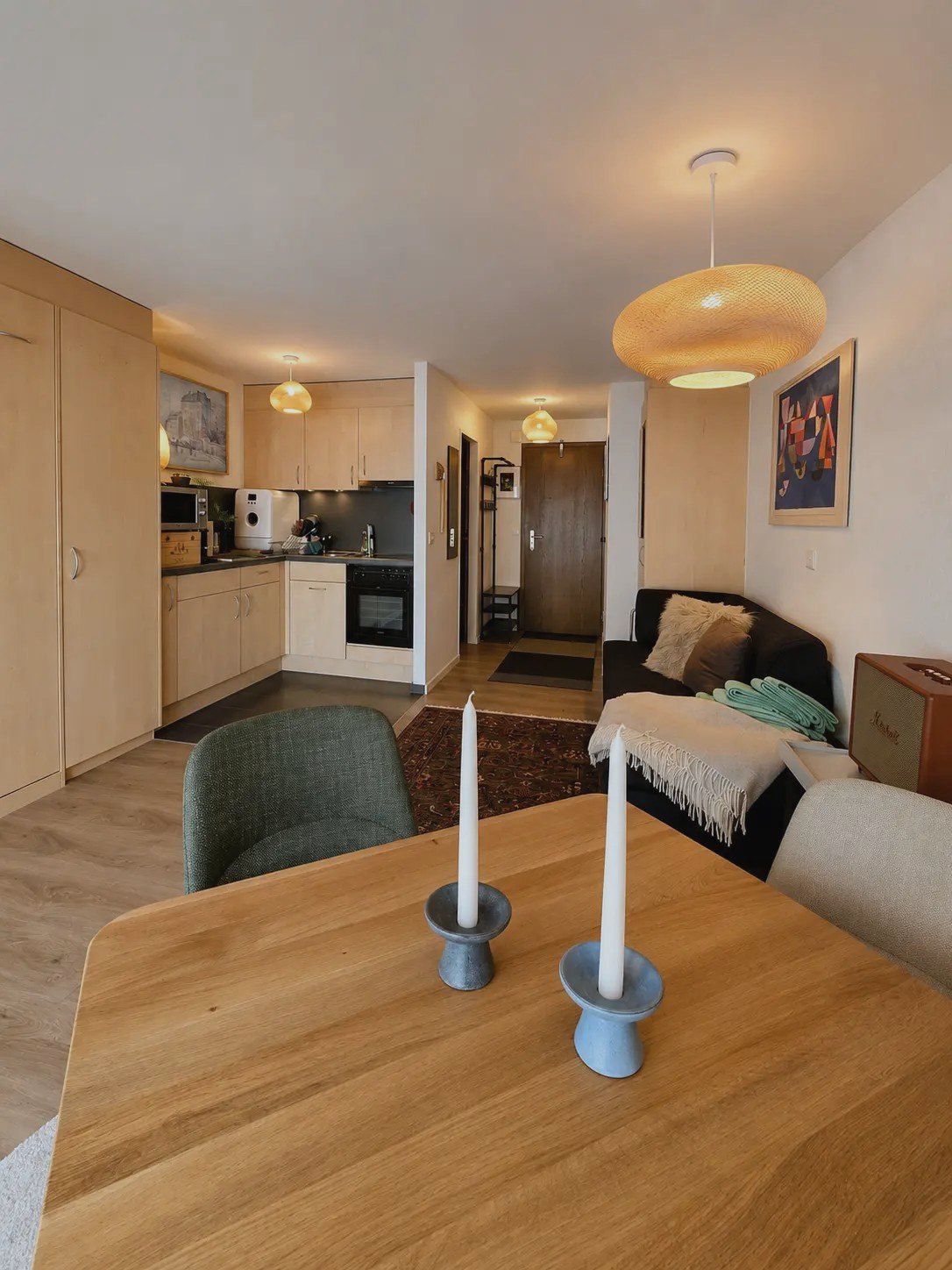 Wohn- und Essbereich des Studios Malo in Saas-Fee mit Holztisch, Sofa und offener Küche