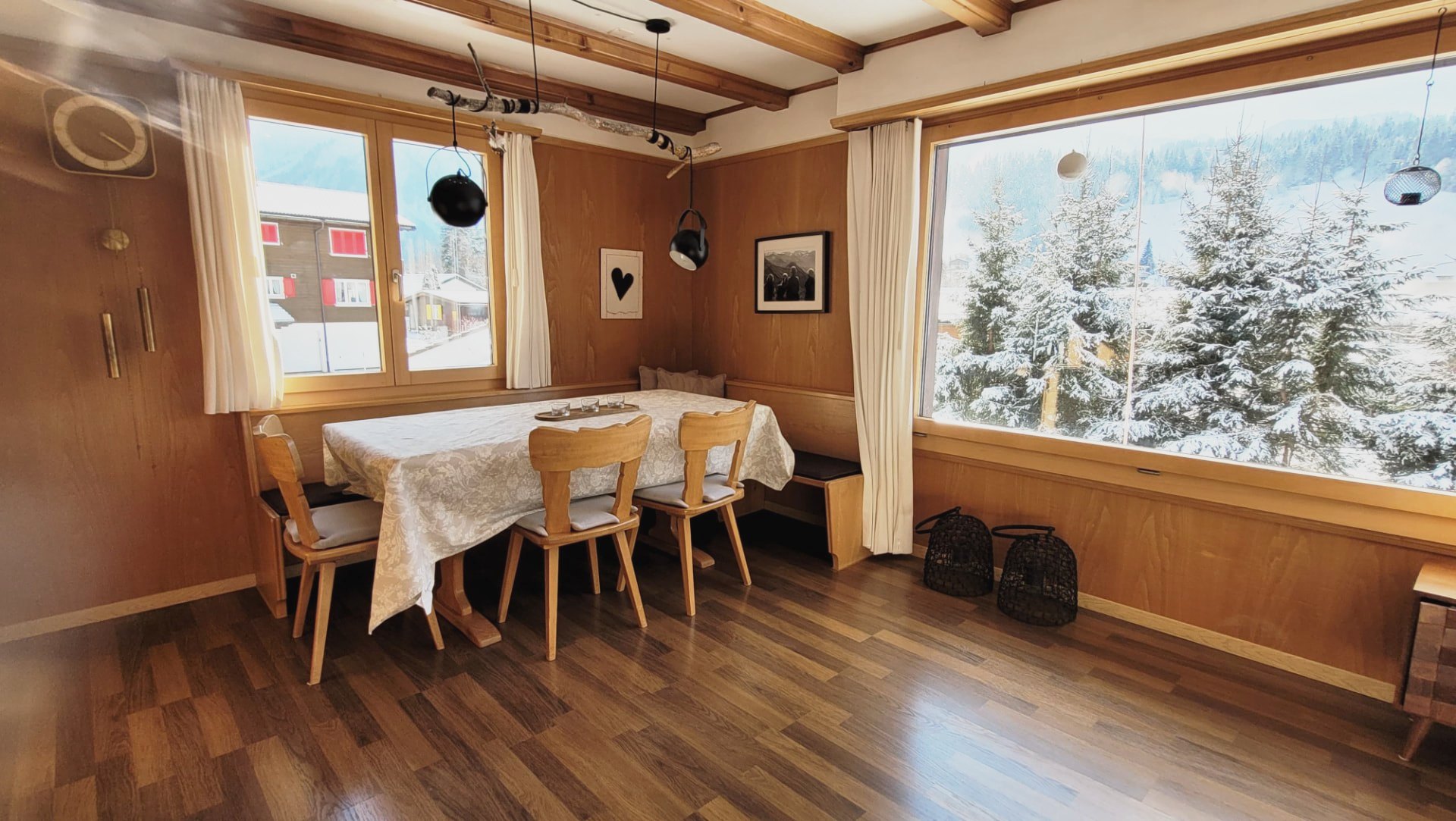 Esstisch im Chalet Nördli vor Panoramafenster mit Blick auf verschneite Tannen und Berge