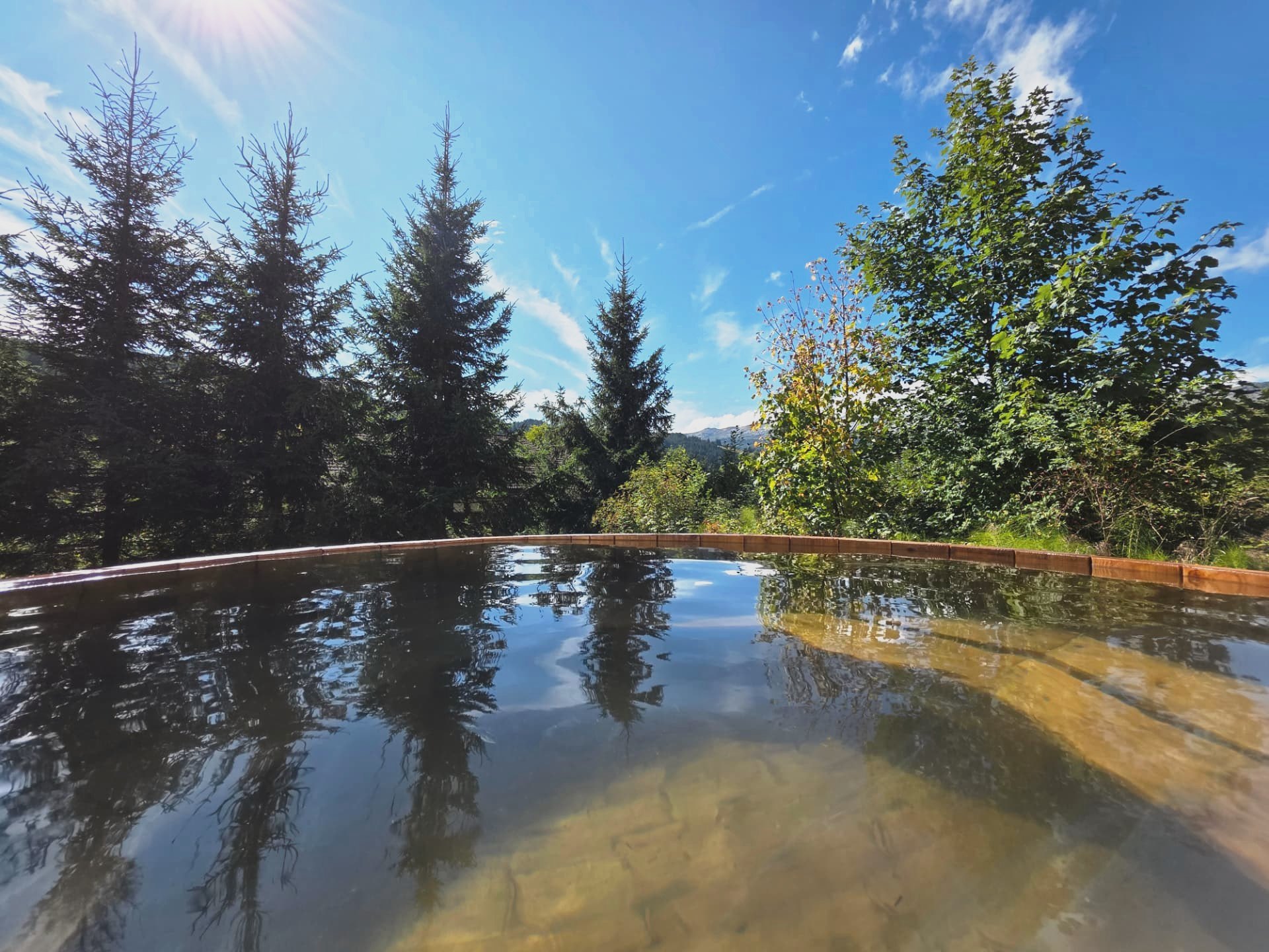 Heisser Hotpot aus Holz im Garten des Chalets Nördli, umgeben von Tannen und Bergwald